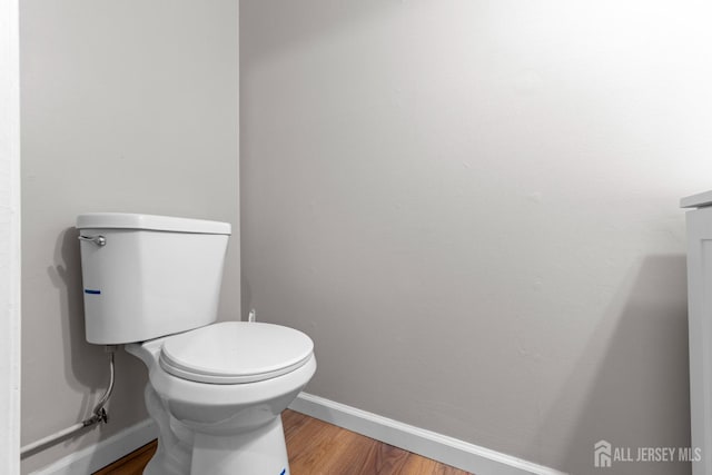 bathroom with toilet, baseboards, and wood finished floors