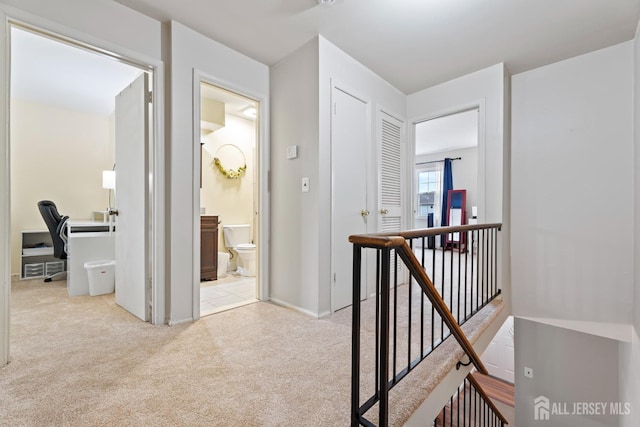 hallway with carpet floors and an upstairs landing