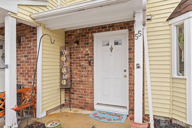 view of exterior entry featuring brick siding and a porch