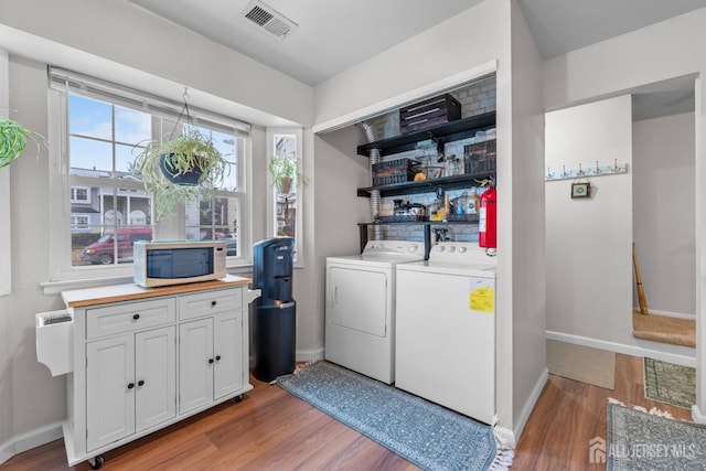 laundry room featuring washing machine and dryer, laundry area, wood finished floors, visible vents, and baseboards