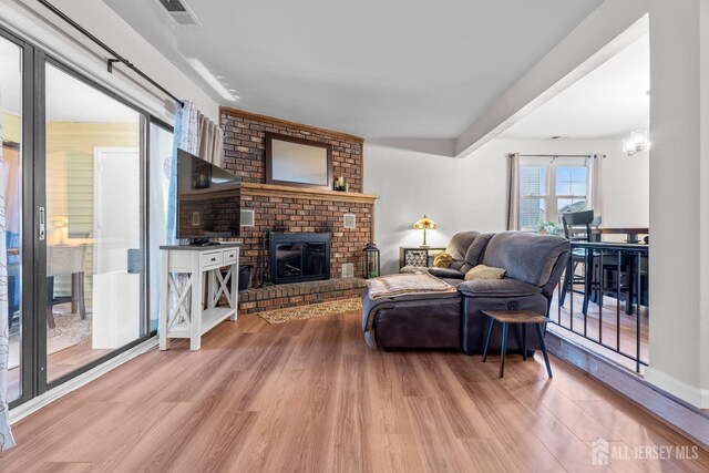 living room featuring visible vents, a fireplace, a notable chandelier, and wood finished floors