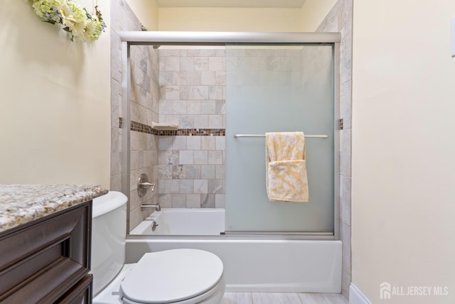 full bathroom featuring bath / shower combo with glass door, vanity, and toilet