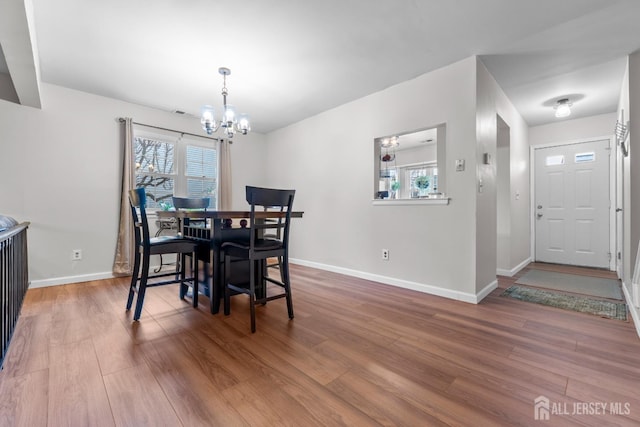 dining room featuring a wealth of natural light, a notable chandelier, baseboards, and wood finished floors