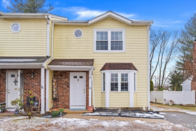 view of front of home featuring brick siding and fence