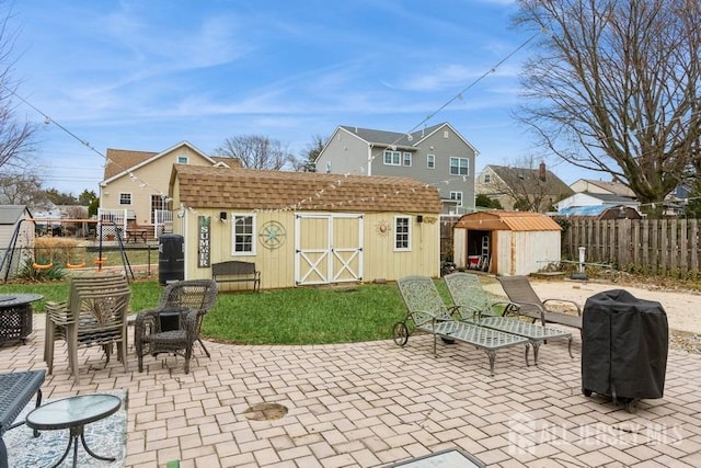 view of patio / terrace with an outbuilding, fence, a storage shed, and area for grilling