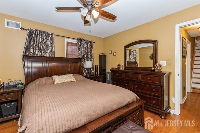 bedroom featuring baseboards, visible vents, light wood-style flooring, and ceiling fan