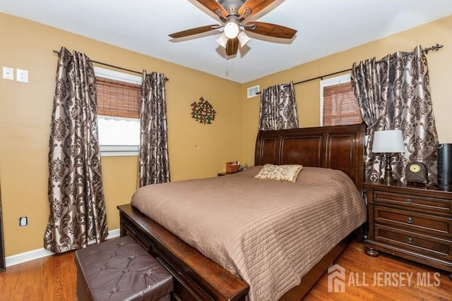bedroom featuring baseboards, visible vents, wood finished floors, and ceiling fan