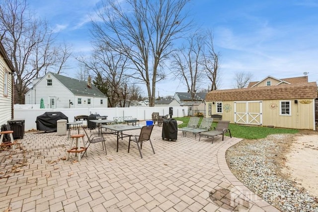 view of patio / terrace with a storage shed, outdoor dining area, a fenced backyard, a grill, and an outdoor structure