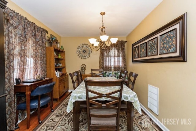 dining area featuring wood finished floors, a chandelier, and visible vents