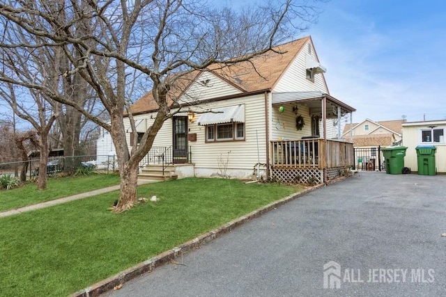 view of front of home featuring a front lawn, fence, and aphalt driveway