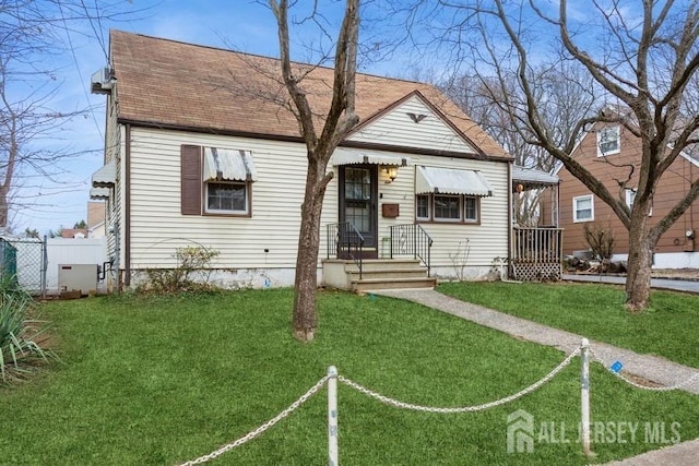 bungalow-style house with a shingled roof, fence, and a front lawn