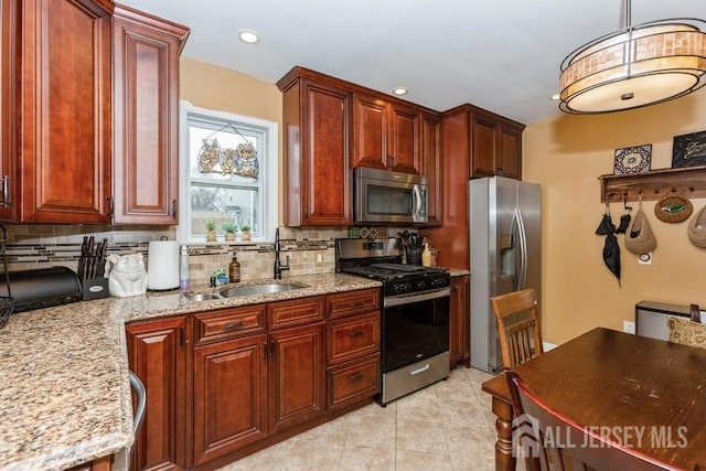 kitchen featuring light stone countertops, a sink, tasteful backsplash, and appliances with stainless steel finishes