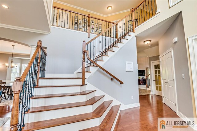 4 Van Gogh Ct, South Brunswick, NJ 08852 - stairway featuring a chandelier, a high ceiling, wood finished floors, crown molding, and baseboards