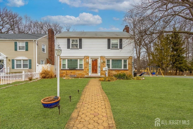 view of front facade featuring a front yard, a playground, fence, and a chimney