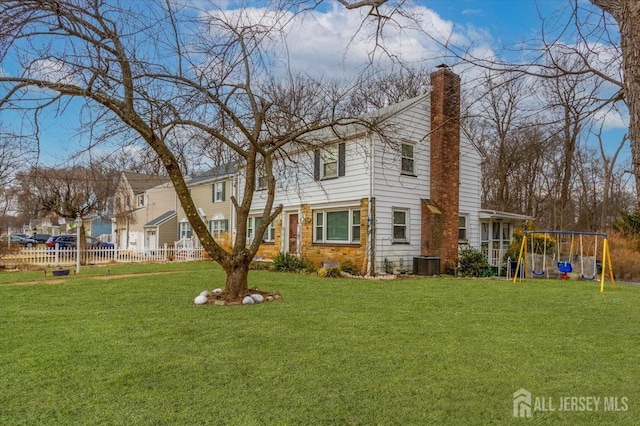 exterior space with a playground, fence, central AC, a chimney, and a yard