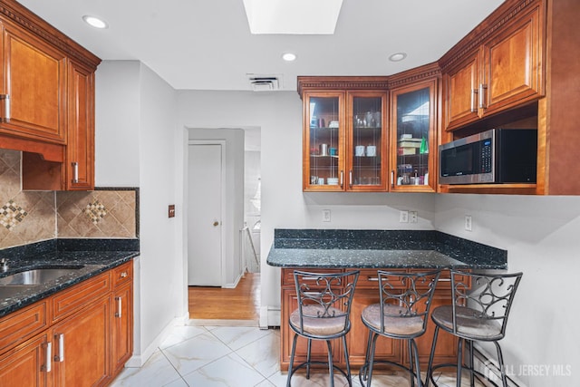 1099 New Dover Rd, Edison, NJ 08820 - kitchen with stainless steel microwave, dark stone counters, light marble finish floors, glass insert cabinets, and a skylight