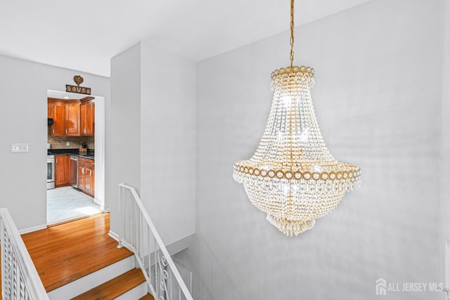 1099 New Dover Rd, Edison, NJ 08820 - detailed view of a chandelier, appliances with stainless steel finishes, decorative backsplash, wood finished floors, and under cabinet range hood