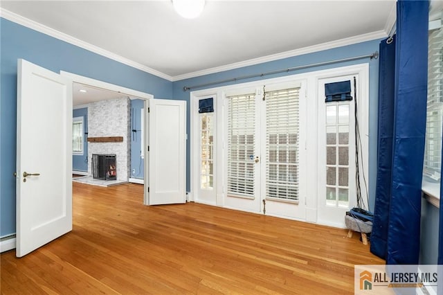 15 Kensington Ave, Trenton, NJ 08618 - empty room featuring wood finished floors, crown molding, a stone fireplace, plenty of natural light, and baseboard heating