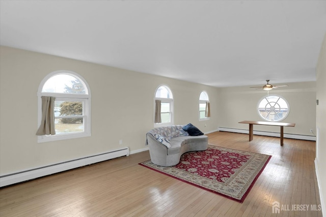 living room featuring a wealth of natural light, baseboard heating, and wood finished floors