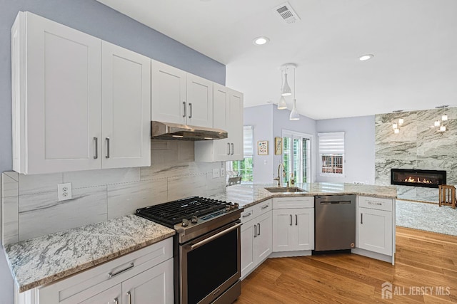 3 Devon Ct, Monroe, NJ 08831 - kitchen featuring stainless steel appliances, a sink, under cabinet range hood, a peninsula, and a high end fireplace