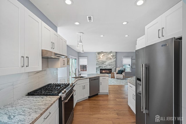 3 Devon Ct, Monroe, NJ 08831 - kitchen featuring appliances with stainless steel finishes, under cabinet range hood, a sink, a high end fireplace, and white cabinets
