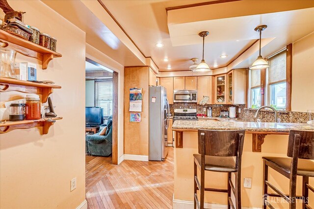 kitchen with light stone countertops, appliances with stainless steel finishes, pendant lighting, and a breakfast bar area