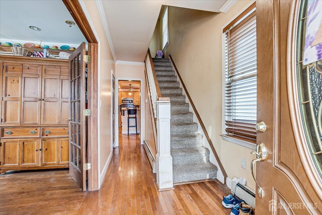 foyer entrance with crown molding, light hardwood / wood-style flooring, and a baseboard heating unit