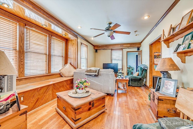 living room featuring crown molding, wood walls, ceiling fan, and light wood-type flooring