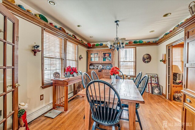 dining space with a baseboard heating unit, light hardwood / wood-style flooring, and a notable chandelier