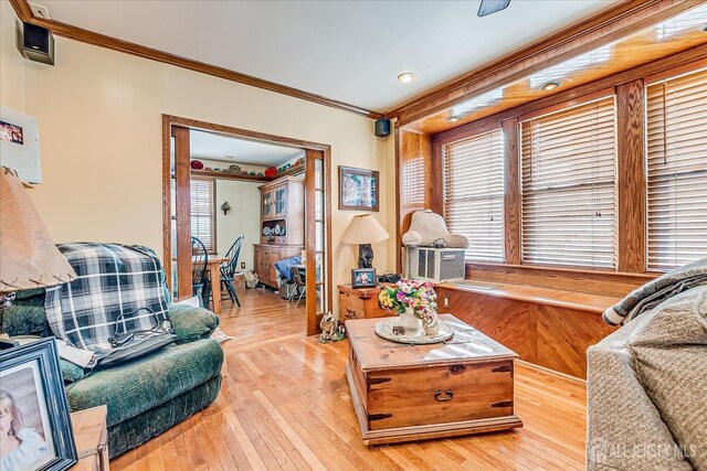 living room featuring crown molding, plenty of natural light, and light hardwood / wood-style floors