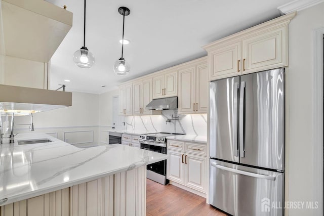 495 Newport Way Unit B, Monroe, NJ 08831 - kitchen featuring a sink, light stone countertops, under cabinet range hood, appliances with stainless steel finishes, and cream cabinets