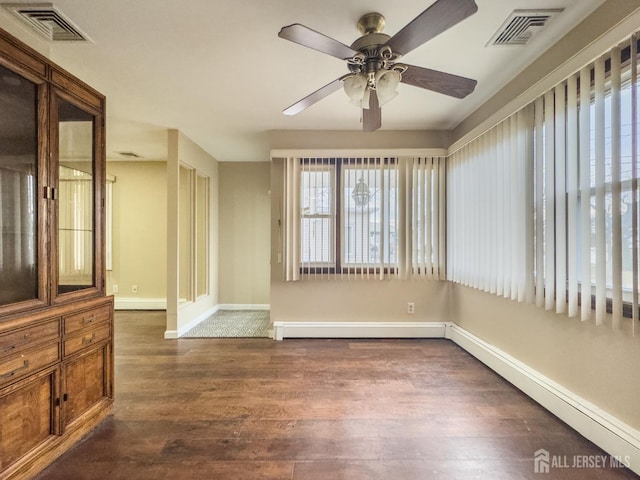 empty room featuring dark hardwood / wood-style flooring, a baseboard radiator, and ceiling fan