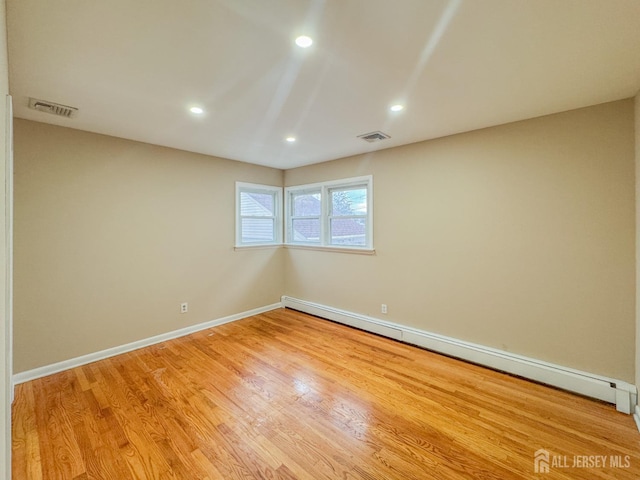 empty room with a baseboard radiator and light hardwood / wood-style floors