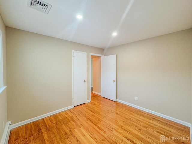 empty room featuring baseboard heating and light wood-type flooring