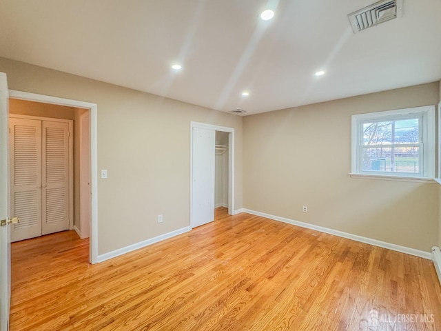 unfurnished bedroom featuring light hardwood / wood-style floors and a baseboard heating unit