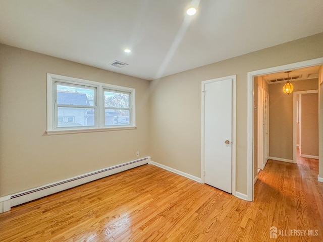 spare room with light hardwood / wood-style floors and a baseboard heating unit