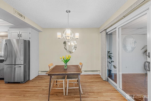 195 Mayflower Way Unit B, Monroe, NJ 08831 - dining space featuring a baseboard heating unit, a textured ceiling, visible vents, and light wood-style flooring