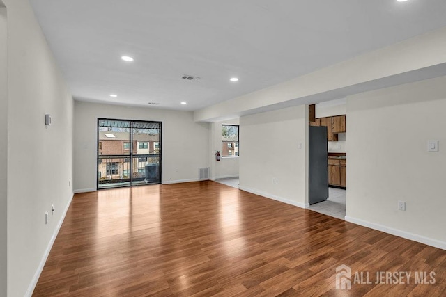 unfurnished living room with light wood finished floors, recessed lighting, visible vents, and baseboards