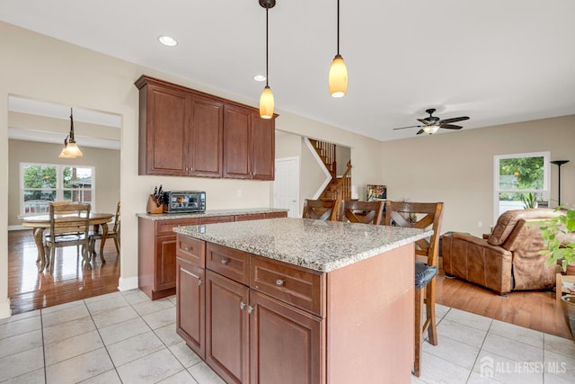 51 N Smith St, Avenel, NJ 07001 - kitchen with a kitchen breakfast bar, light tile patterned floors, open floor plan, decorative light fixtures, and light stone counters