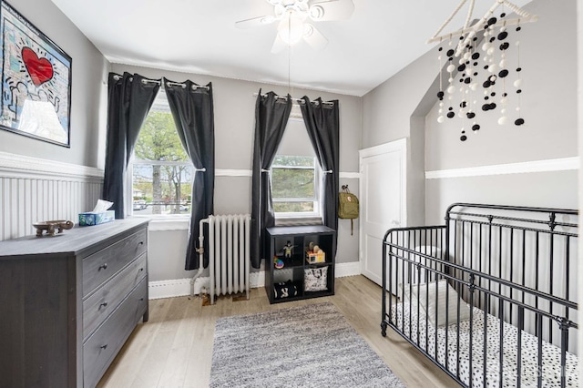 1402 Glenwood Dr, Piscataway, NJ 08854 - bedroom featuring radiator, a crib, light wood-style floors, baseboards, and a ceiling fan