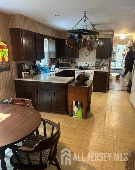 188 N Rd, Chester Twp, NJ 07930 - kitchen featuring wallpapered walls, stainless steel microwave, light countertops, dark brown cabinetry, and white range with electric stovetop