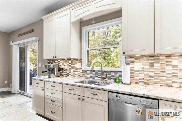 kitchen featuring dishwasher, light stone counters, white cabinetry, and sink