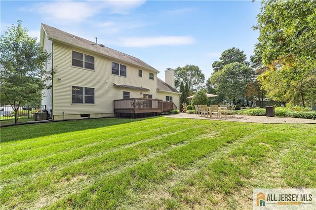 rear view of property featuring a yard, a patio, and a wooden deck