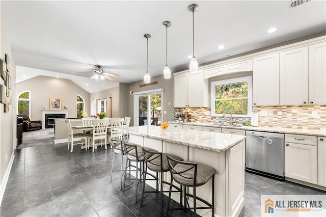 kitchen featuring ceiling fan, hanging light fixtures, stainless steel dishwasher, lofted ceiling, and a kitchen island