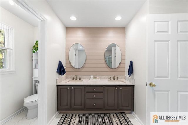 bathroom with wooden walls, tile patterned flooring, vanity, and toilet