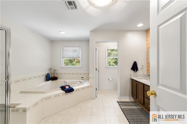 bathroom with tile patterned floors, vanity, and tiled bath