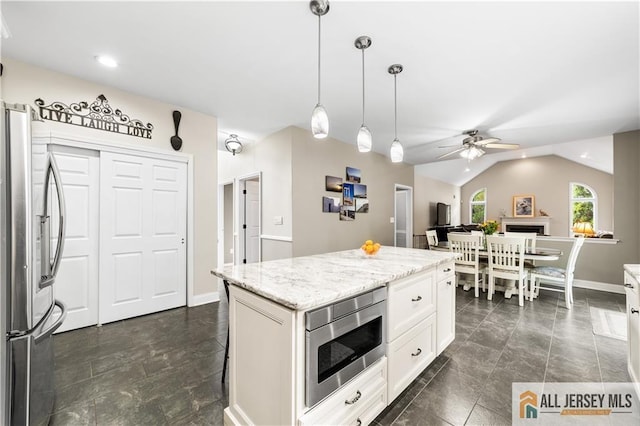 kitchen with stainless steel refrigerator, built in microwave, decorative light fixtures, vaulted ceiling, and white cabinets