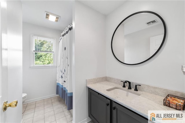 bathroom with tile patterned flooring, vanity, toilet, and walk in shower