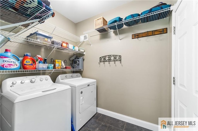 laundry room featuring washer and dryer and dark tile patterned floors