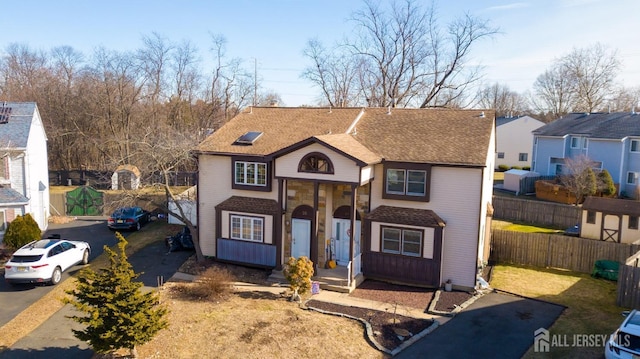 traditional home featuring a shingled roof and fence